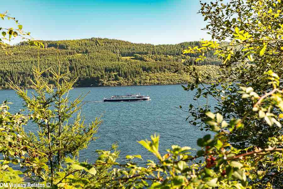 Barco navegando por el Lago Ness entre bosques de las Highlands de Escocia