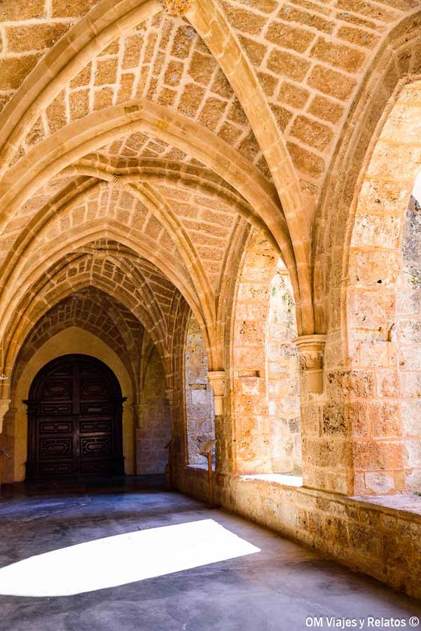 Galería del claustro cisterciense del Monasterio de Piedra, con bóvedas de crucería, arcos de piedra y una puerta de madera