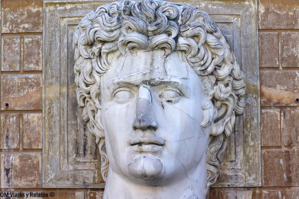 Cabeza de mármol de una escultura clásica masculina, con cabello rizado y detalles del rostro, en los Museos Vaticanos