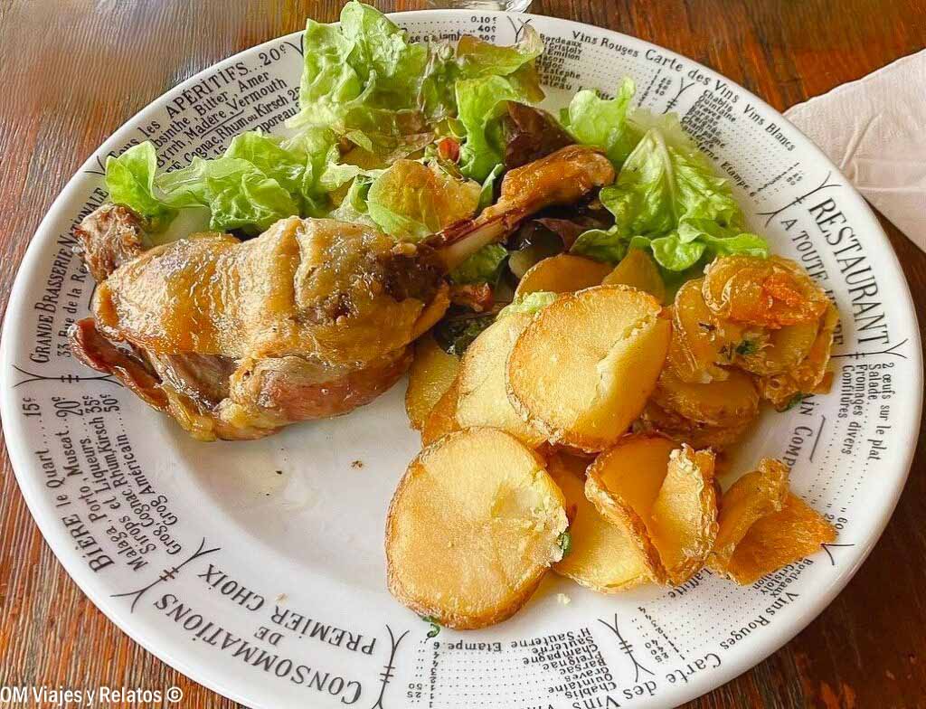 Plato de confit de pato con patatas asadas y ensalada en un restaurante de París