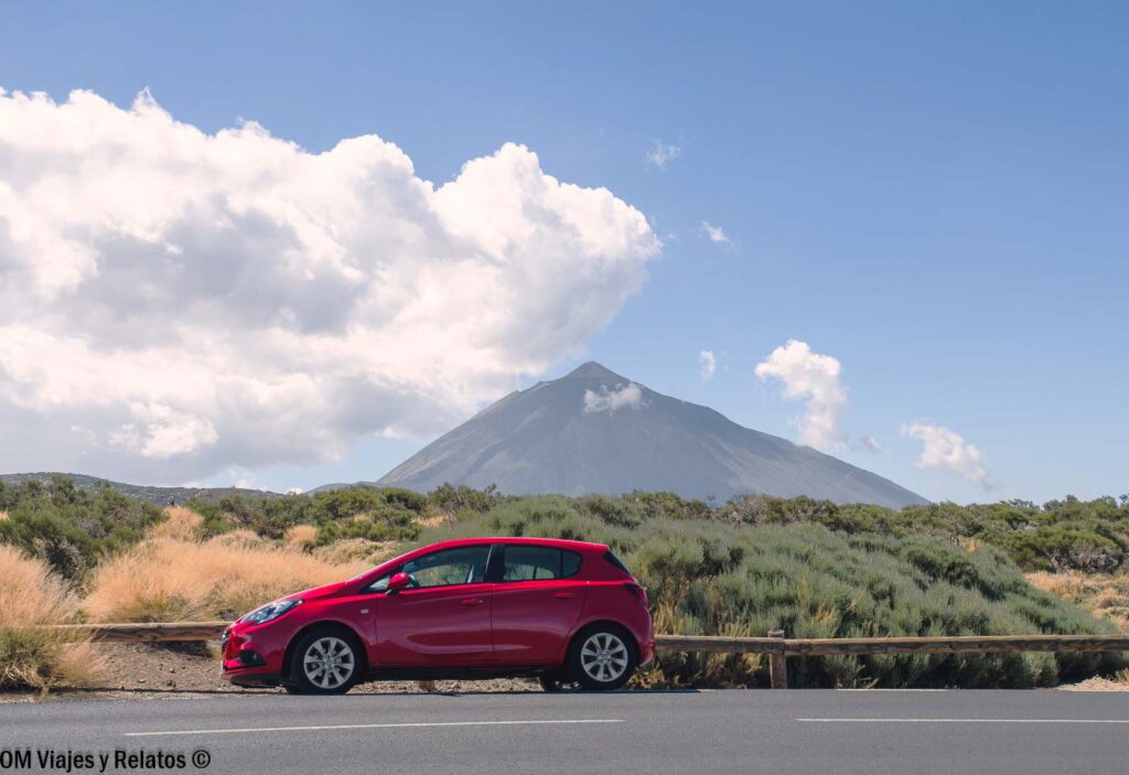 Coche de alquiler rojo aparcado junto a la carretera con el volcán Teide al fondo, imagen para ilustrar consejos para alquilar coche en Tenerife