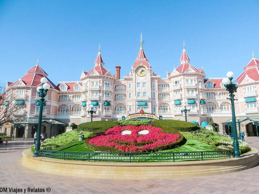 Entrada principal de Disneyland París, con el Disneyland Hotel de color rosa y un jardín floral de Mickey Mouse