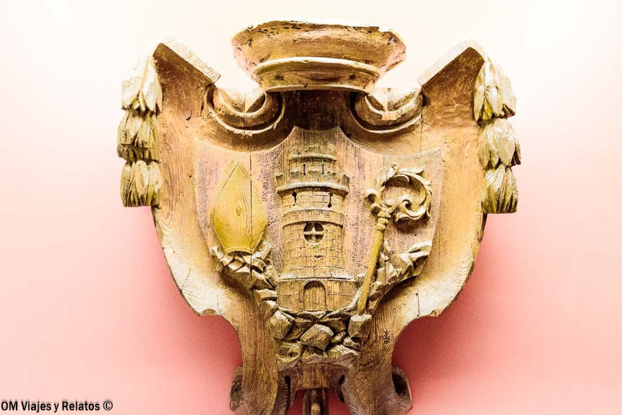 Escudo histórico tallado en piedra con una torre central y símbolos religiosos en el Monasterio de Piedra, Zaragoza