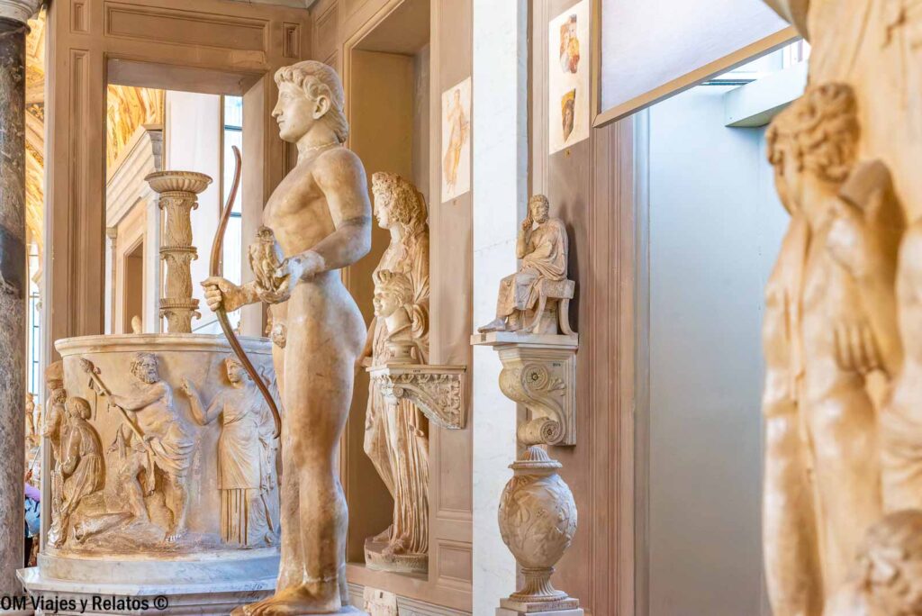 Escultura clásica de un arquero con arco y otras obras de mármol expuestas en una galería de los Museos Vaticanos