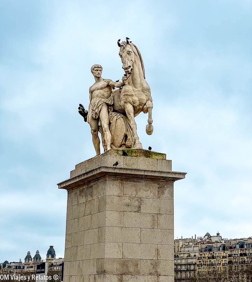 Escultura de un hombre junto a un caballo encabritado sobre un pedestal de piedra en París