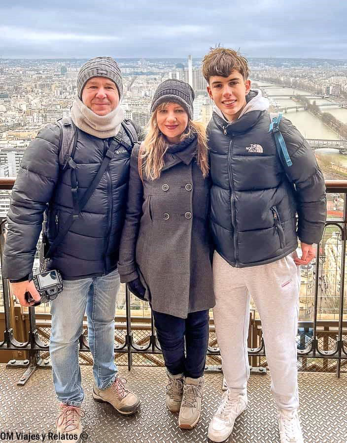 Foto en familia de OM Viajes y Relatos en el mirador de la Torre Eiffel, con vistas panorámicas de París y el río Sena al fondo