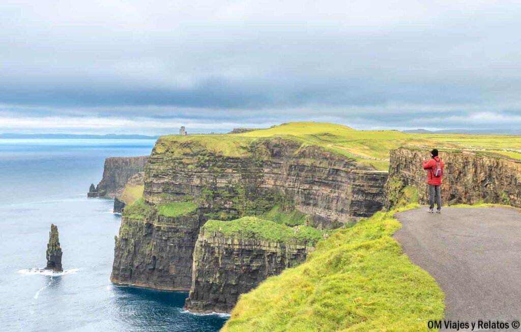 JC fotografiando los Acantilados de Moher en Irlanda desde un mirador, con las enormes paredes rocosas y el océano Atlántico de fondo