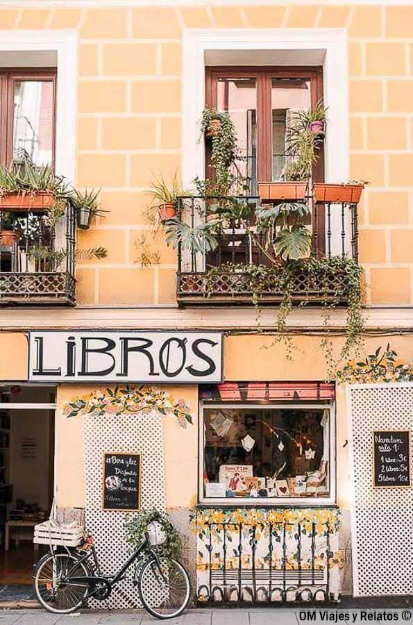 Fachada de una librería en el barrio de Malasaña de Madrid, con balcones llenos de plantas y una bicicleta junto a la entrada