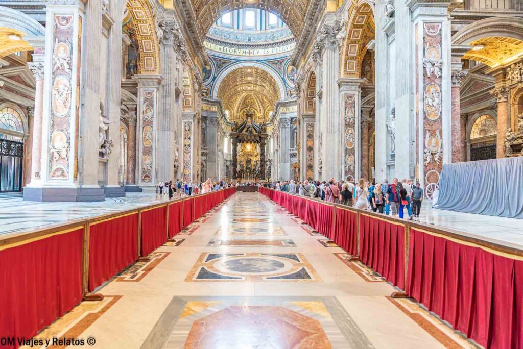 Vista de la nave central de la Basílica de San Pedro en el Vaticano, con sus enormes columnas, bóvedas decoradas y el baldaquino de Bernini al fondo