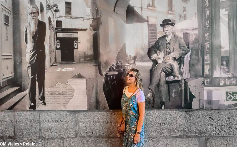 Una servidora junto a un mural en blanco y negro con retratos de escritores históricos en una calle de Madrid
