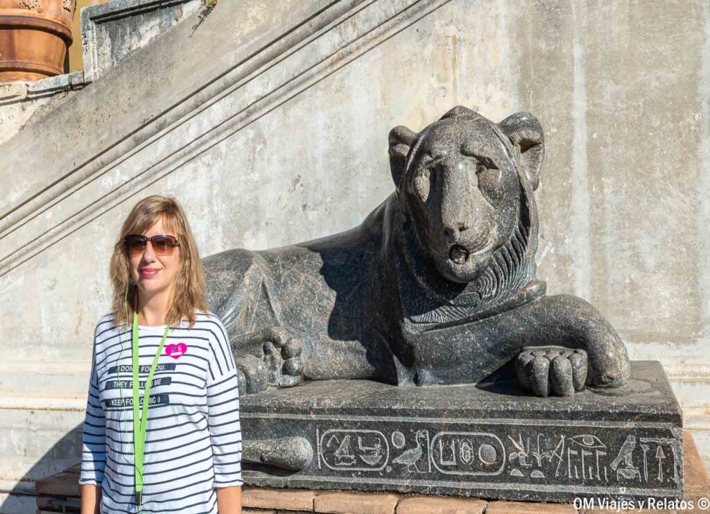 Una servidora junto a una escultura de león egipcio con inscripciones jeroglíficas en el Patio de la Piña de los Museos Vaticanos