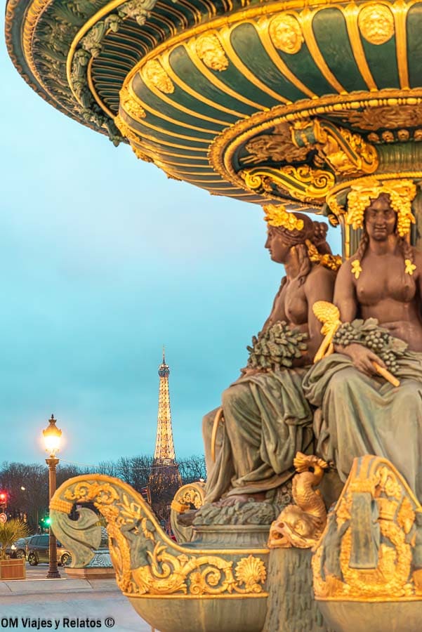 Fuente monumental de la Plaza de la Concordia de París con la Torre Eiffel iluminada al fondo