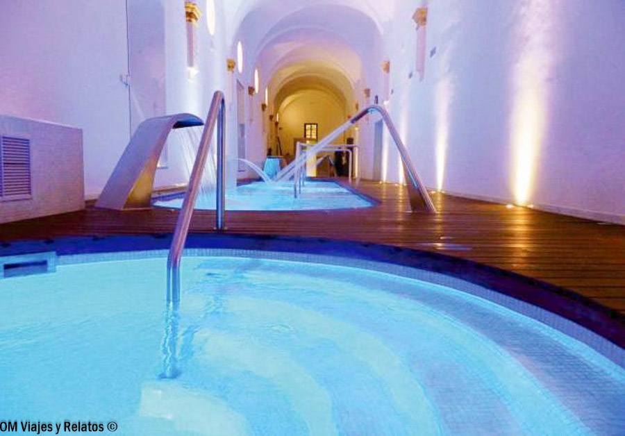Spa del Hotel Monasterio de Piedra, con piscinas de hidromasaje, chorros de agua y una sala abovedada iluminada