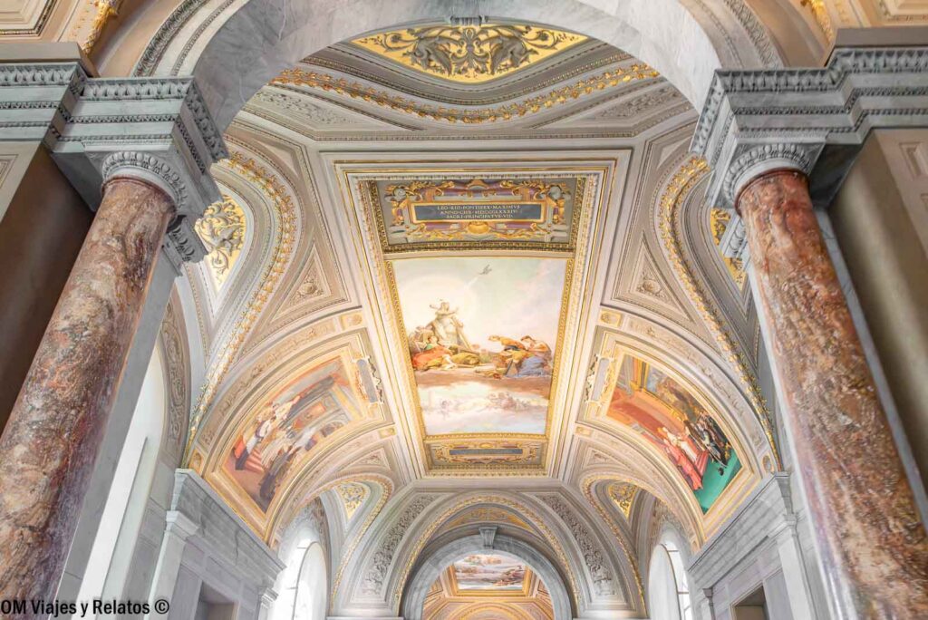 Techos con frescos y detalles dorados en una galería de los Museos Vaticanos, enmarcados por columnas de mármol