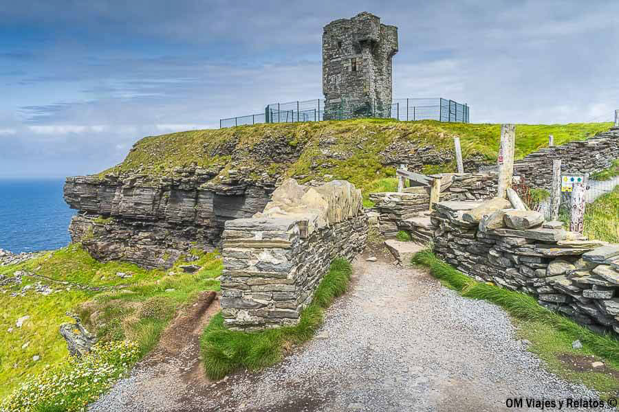 Antigua Torre de Moher en Hag's Head, rodeada de muros de piedra y praderas verdes junto al océano Atlántico